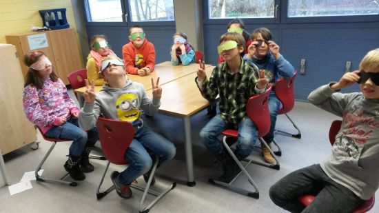 Kinder mit Augenmaske ertasten Gegenstände