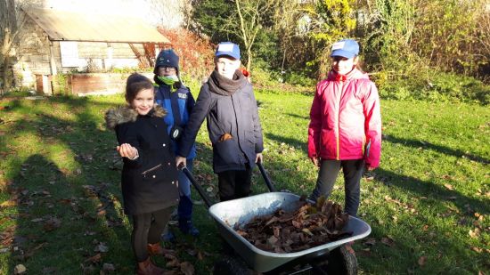 Kinder fahren Laub in Schubkarre