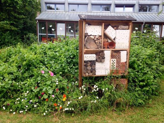 Insektenhotel in Blumenbeet an Teichrand